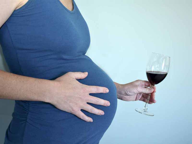 pregnant woman holding glass of wine