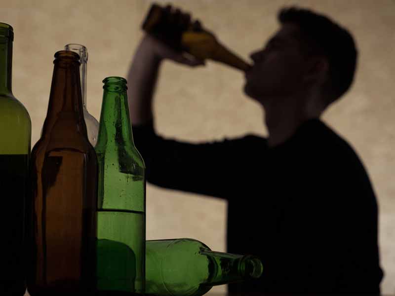 shadow of young man drinking from large bottle
