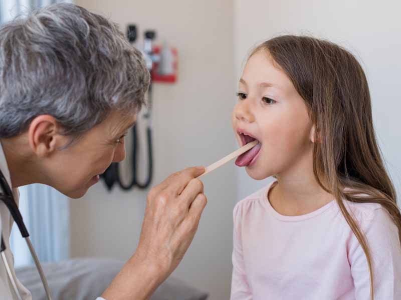 physician examining young girl's throat