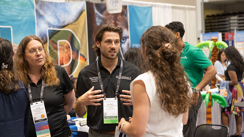 Exhibitors discuss their program with a 2023 National Conference attendee.