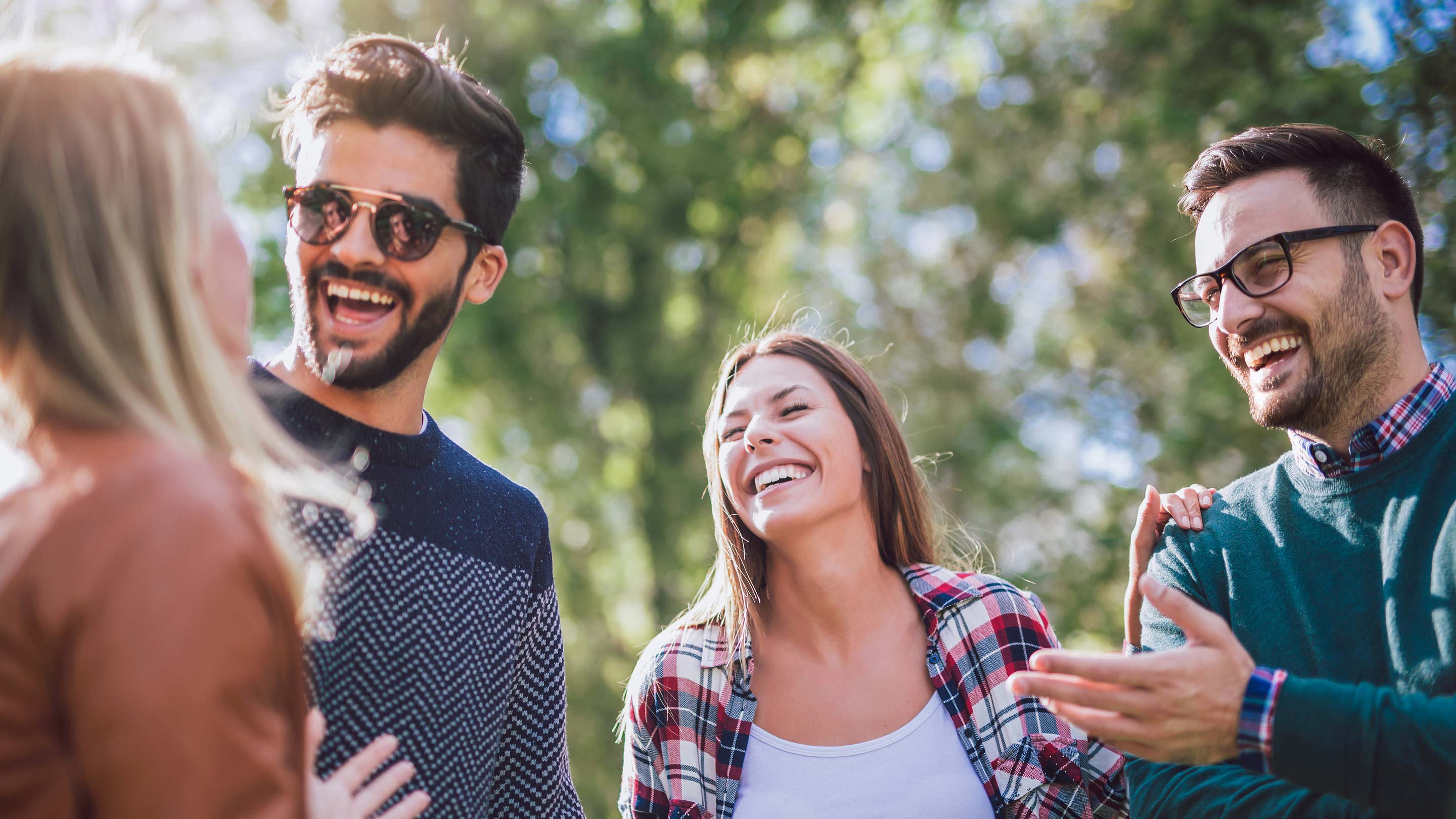 Four friends talking and smiling outdoors.