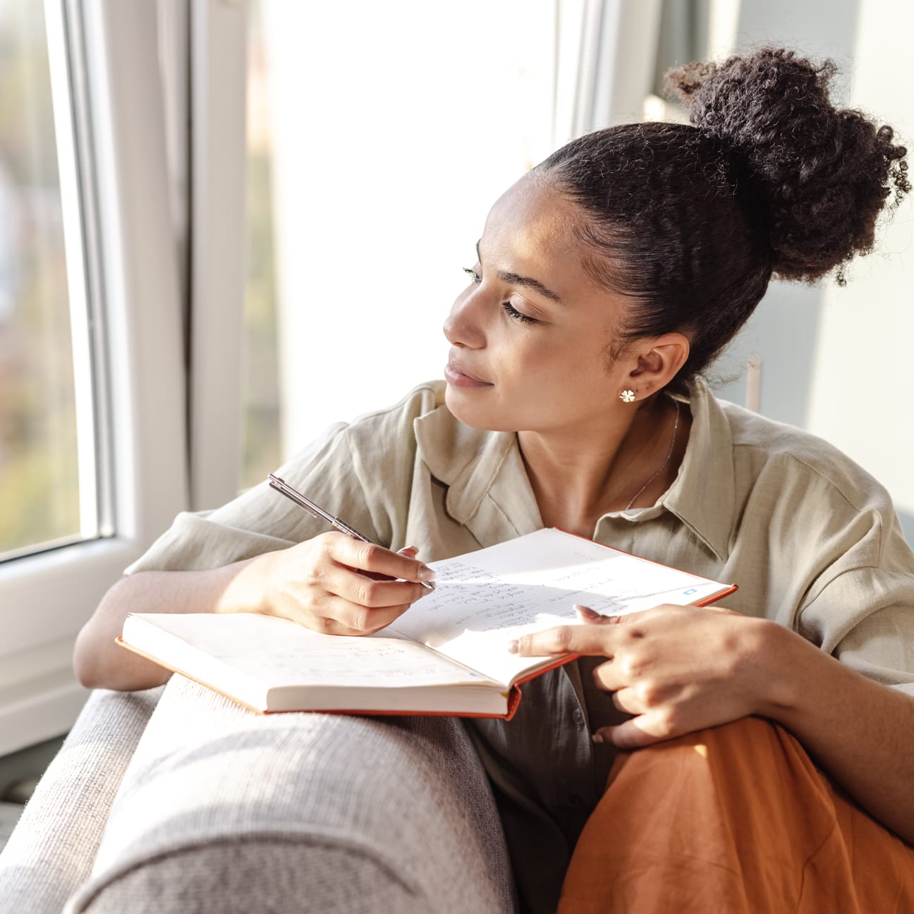 Image of woman relaxing and writing in a notebook.