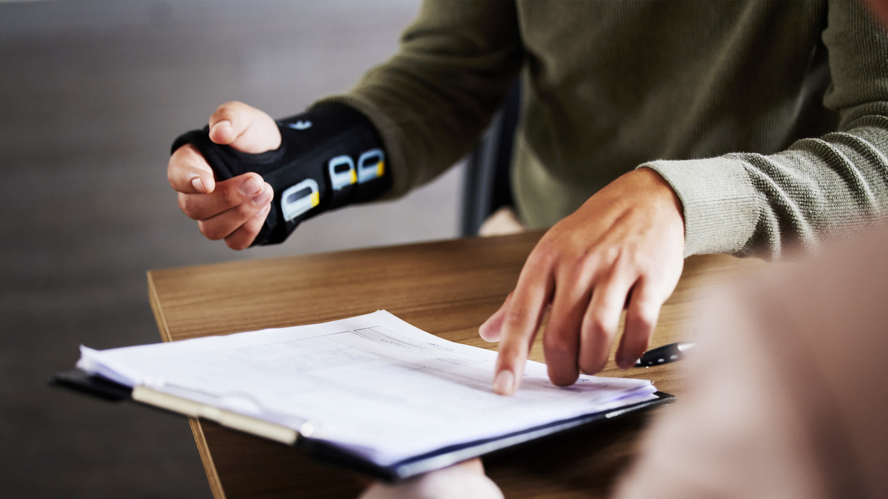 Injury, compensation and hands with insurance documents, legal contract and paperwork.