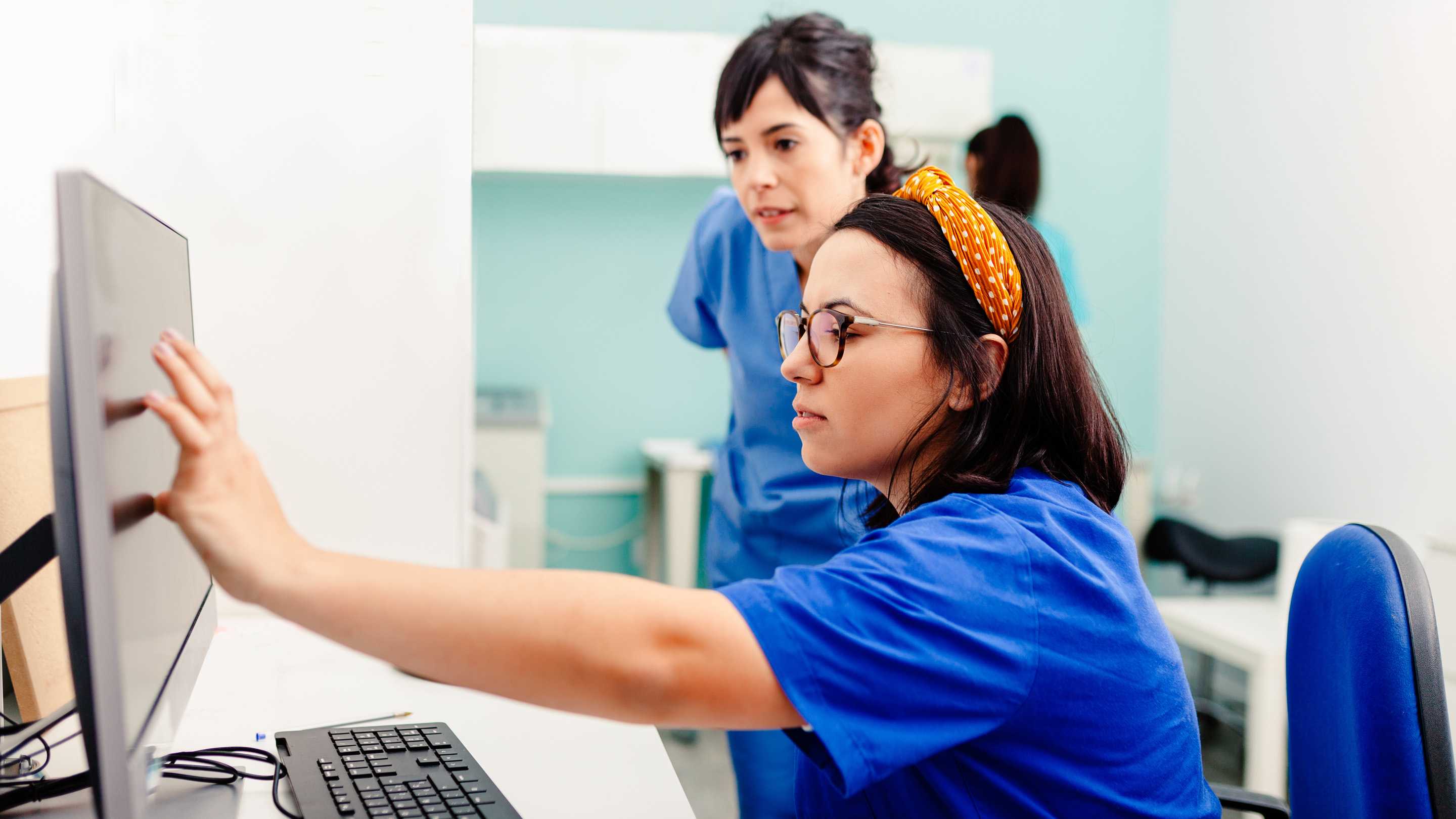 Two physicians talking while pointing at a computer screen.