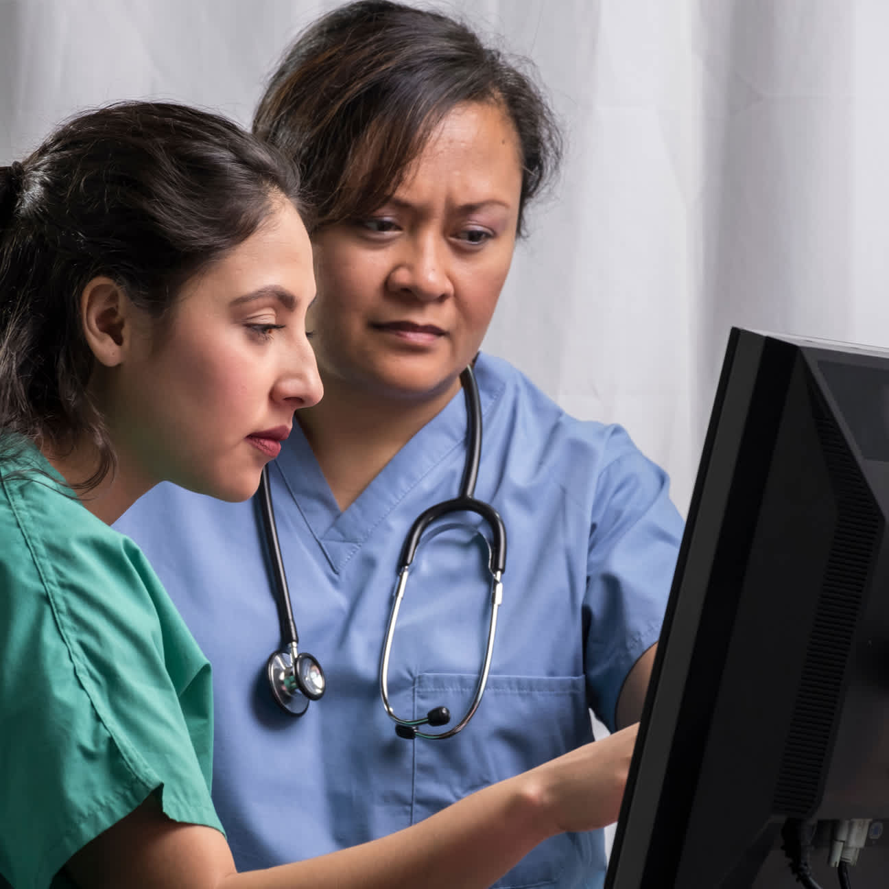 Physicians discussing something while pointing at a computer screen