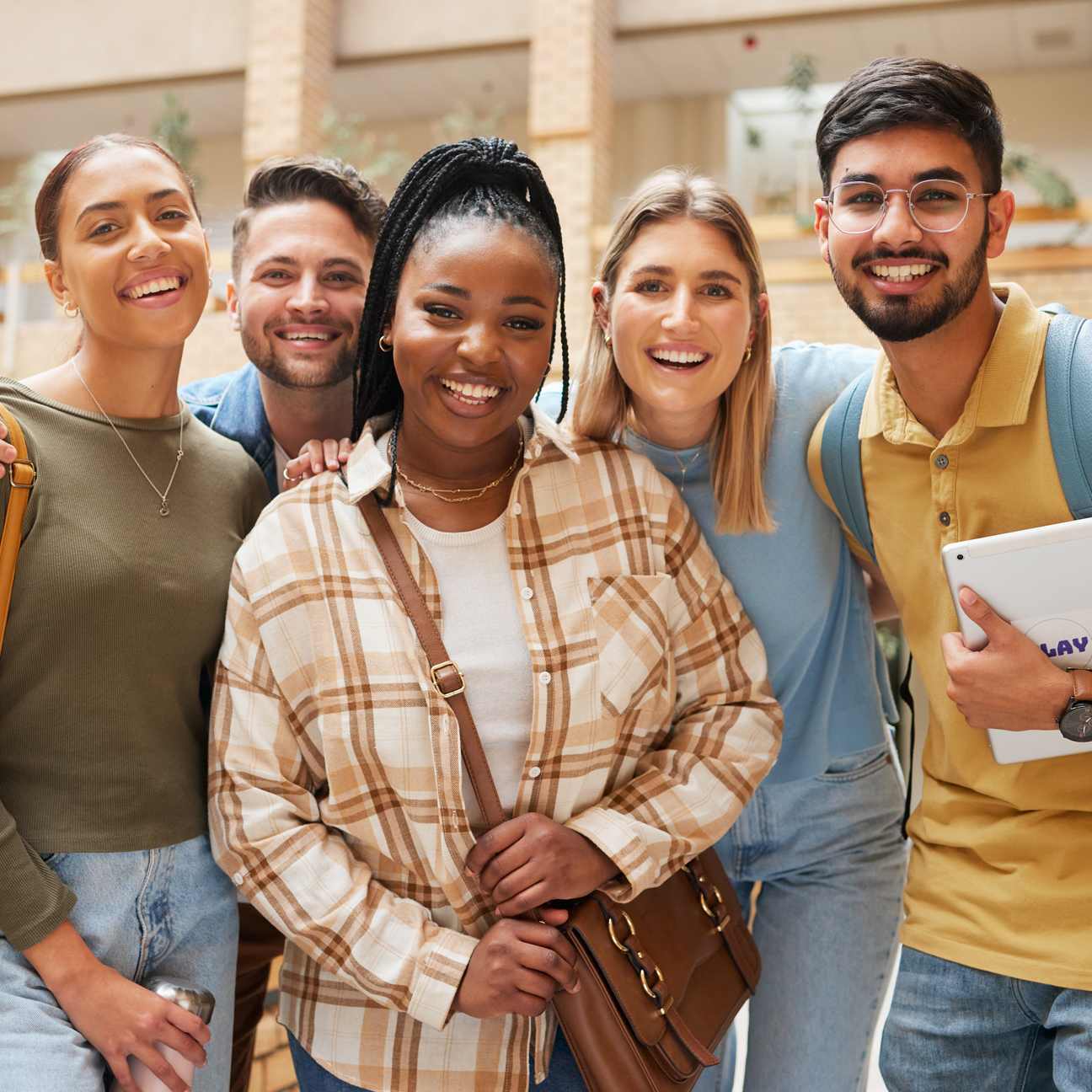 Students and group of friends smiling and standing on a set of stairs outside