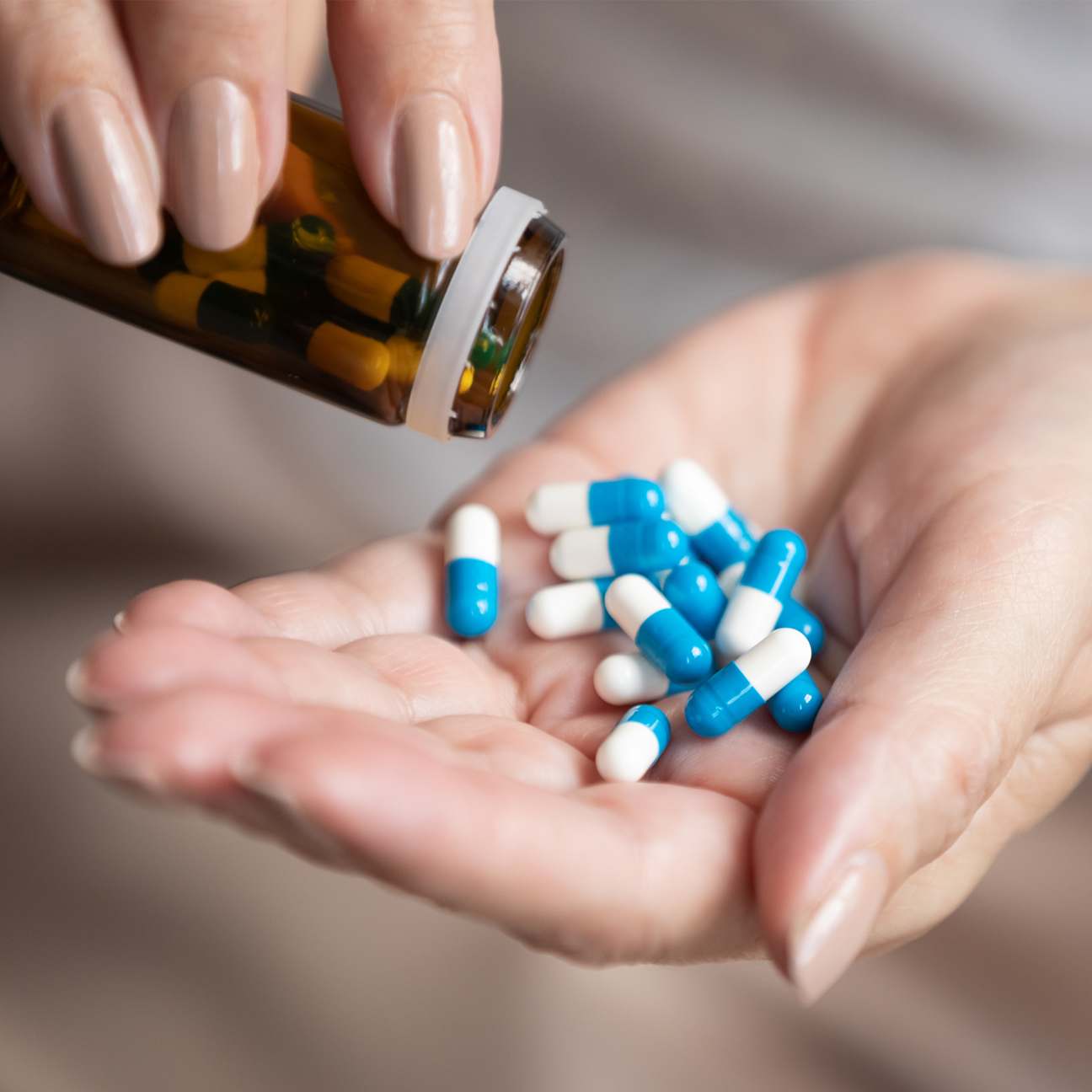 Close up of hands pouring pills from a pill bottle.