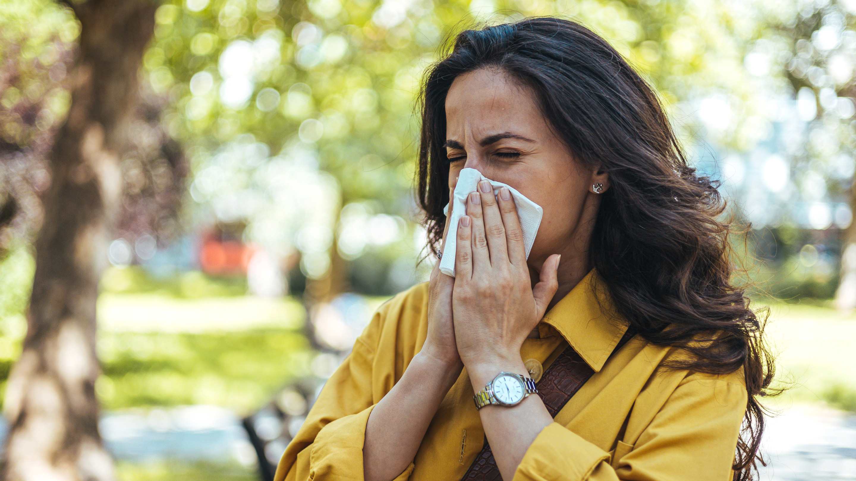 Close up of young woman using tissues, blowing runny nose.