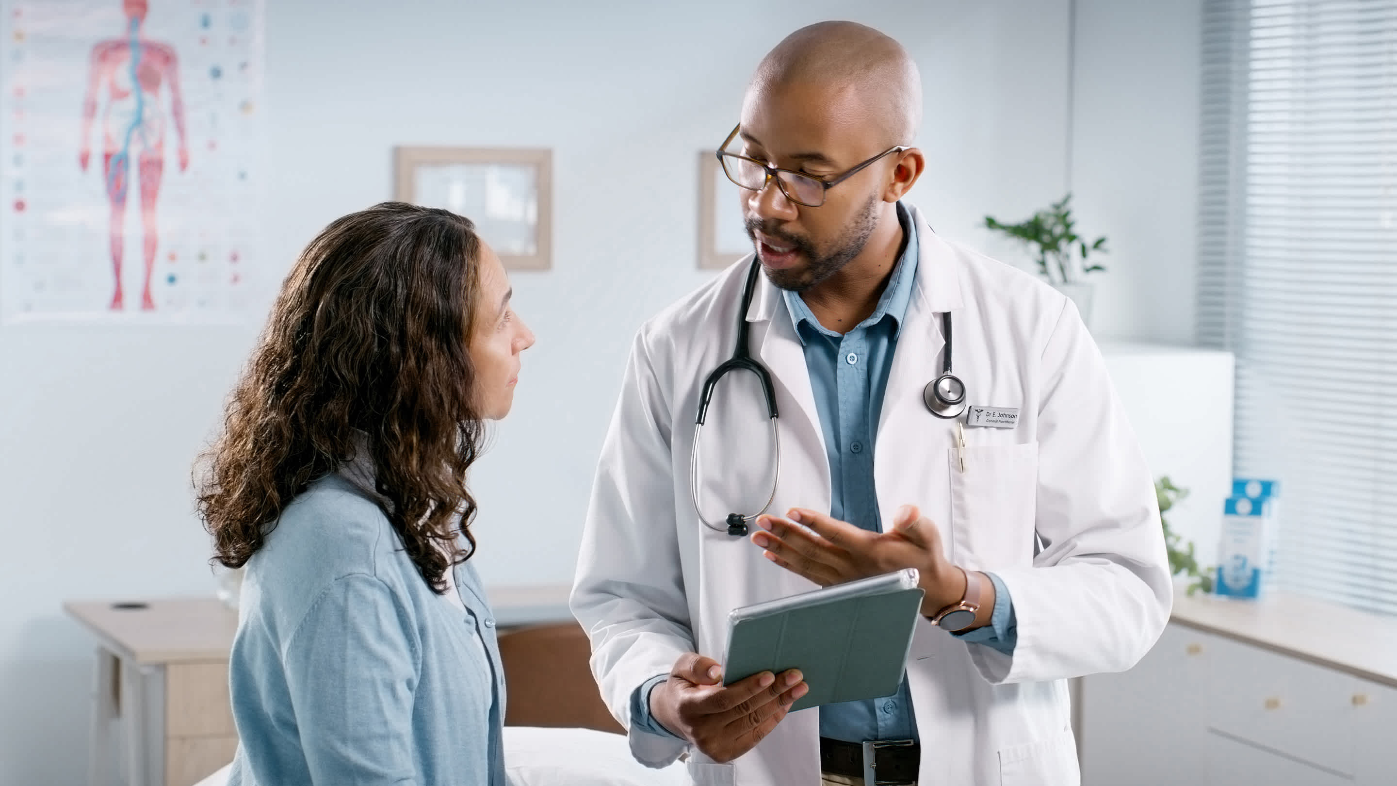 A family doctor talking to an adult patient (patient aged in 30s or 40s) in a clinic.