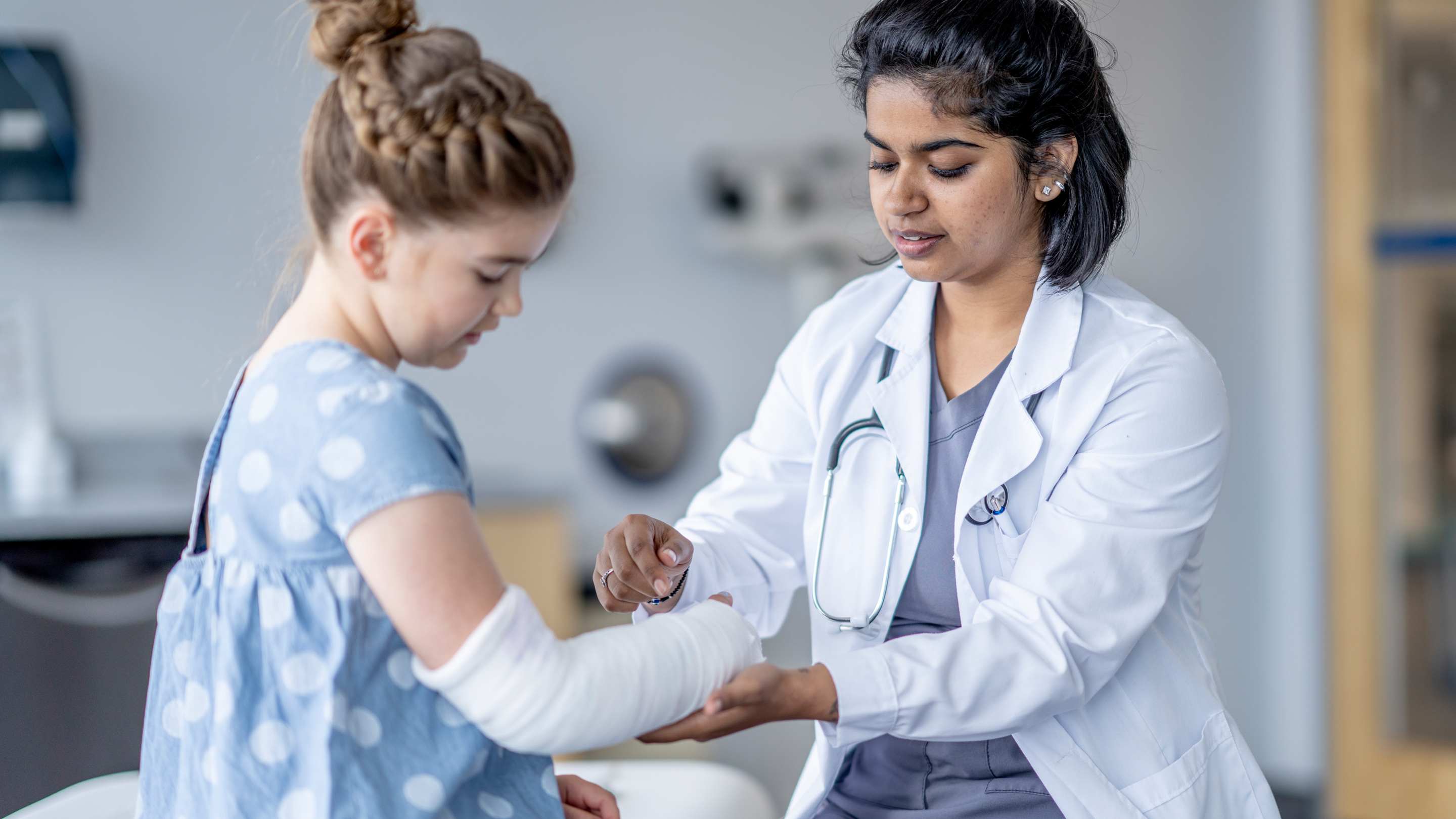 Image of a family physician wrapping an arm injury, putting on a splint.