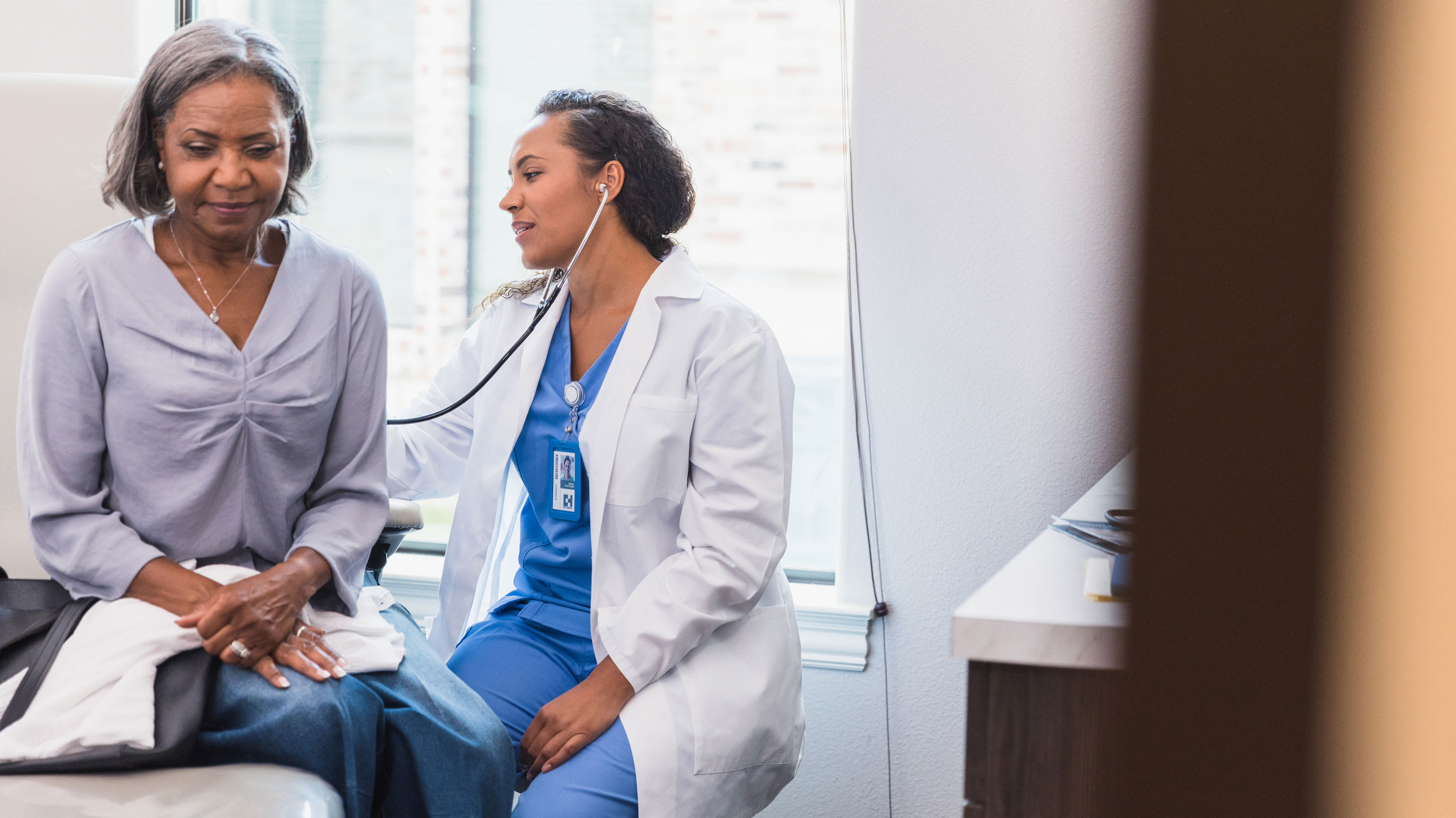Image of female physician listening to the breathing of a mature female African American patient.