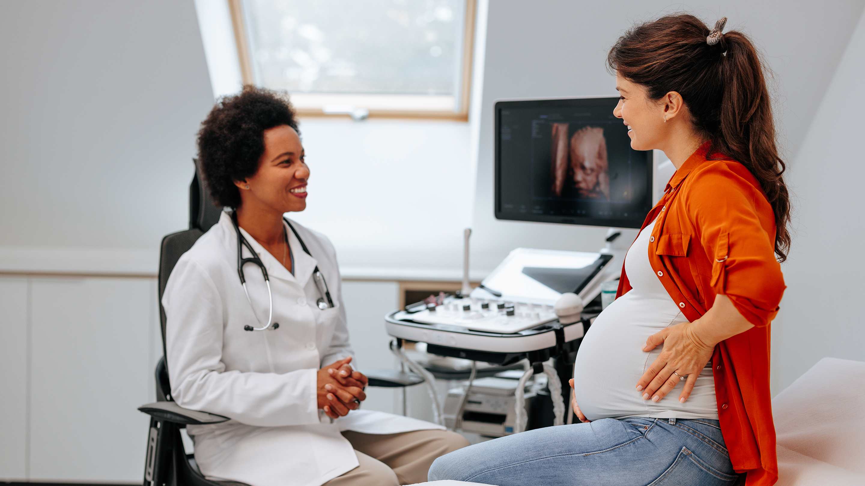Cheerful physician talking to pregnant patient.