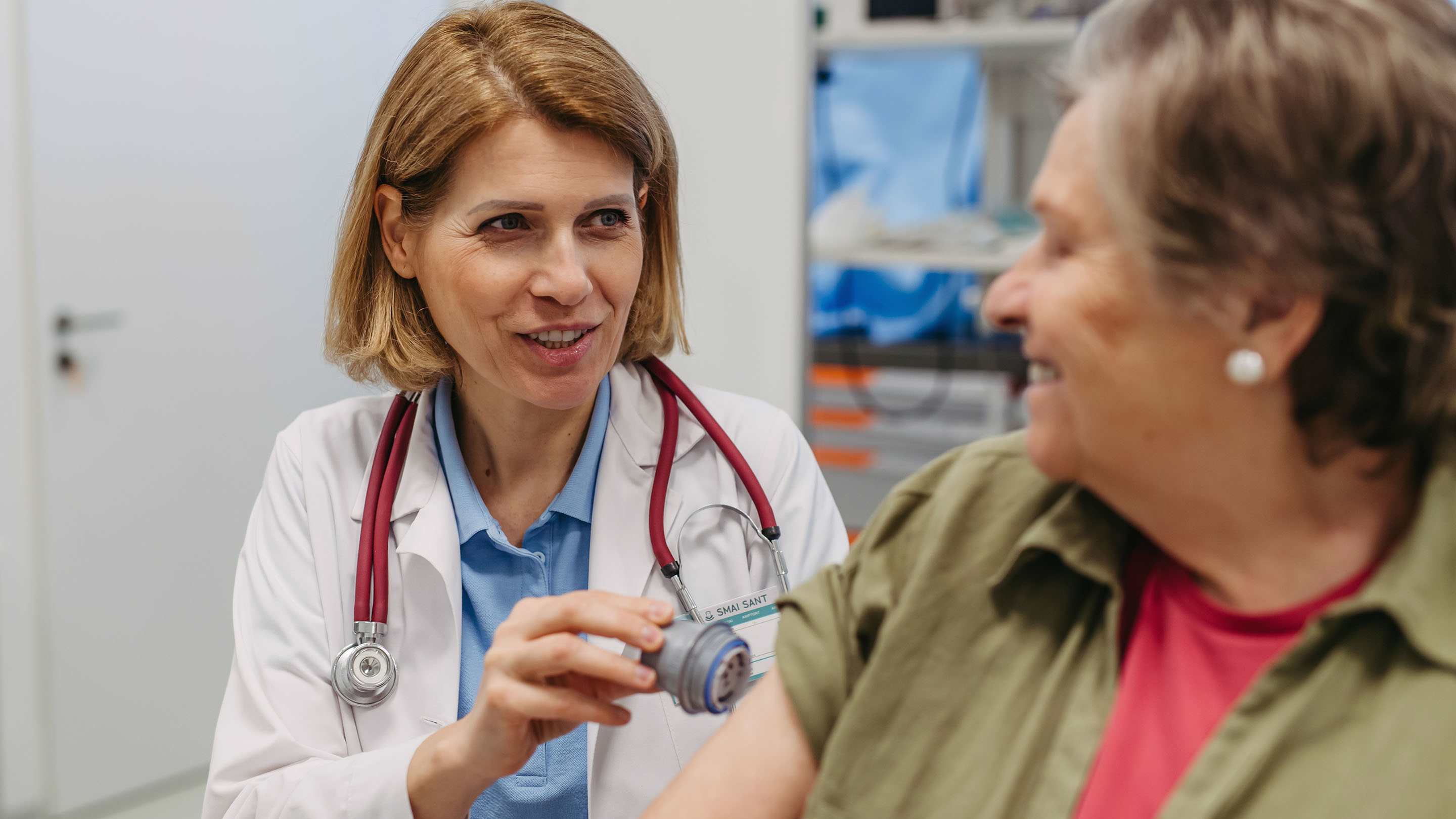 A woman doctor applies a CGM sensor to a senior patients arm.