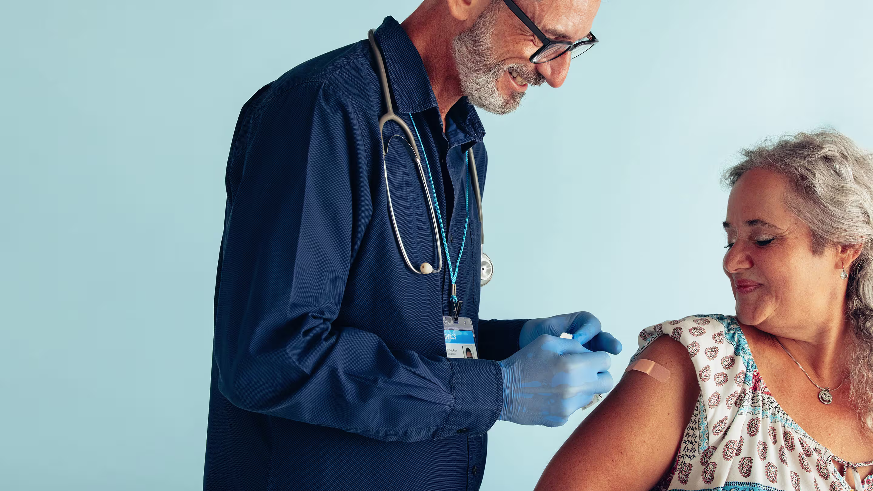 Doctor puts a bandaid on a female patient's arm after a shot or vaccination.