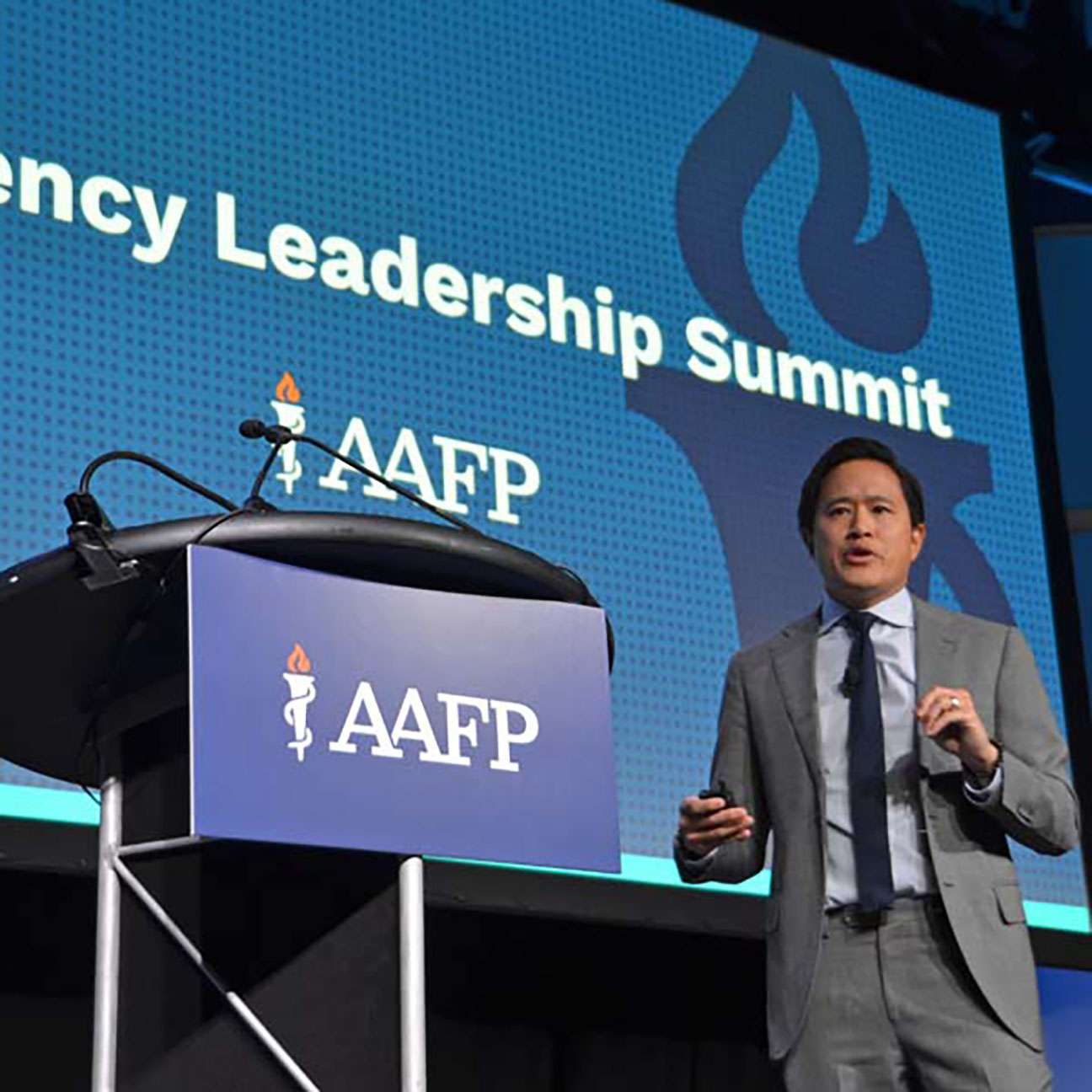 A man in a suit stands in front of a projected graphic that says Residency Leadership Summit.