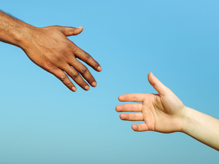 54968577 - black hand man helping white person - different skin color hands united against racism and racial problem - concept of humane aid between different cultures and religion - friendship between peoples