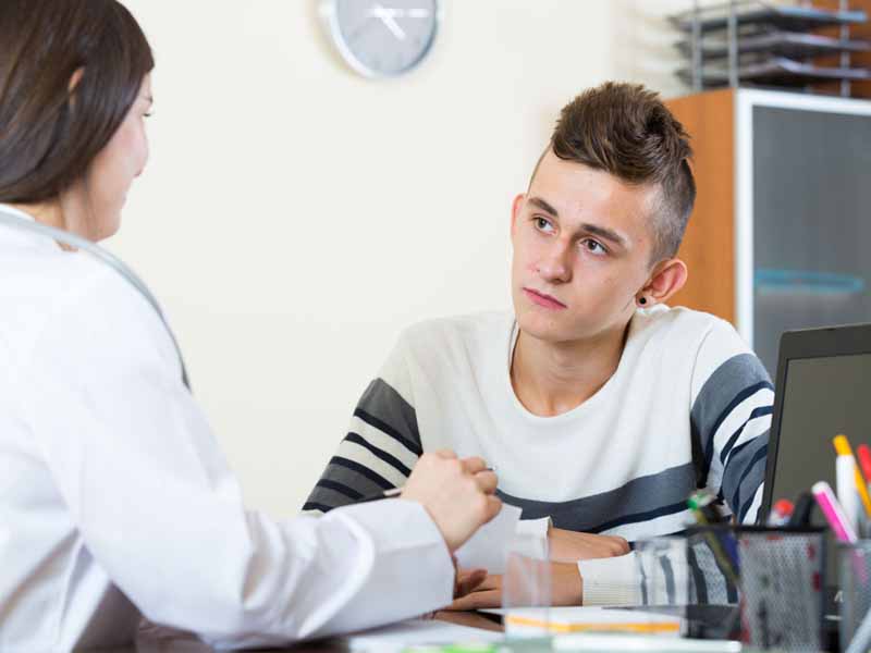 teen boy speaking with female physician