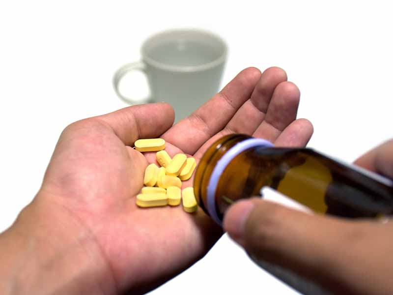 patient shaking pills out of bottle into hand