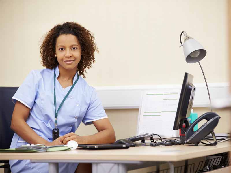 Portrait Of Female Nurse Working At Desk In Office