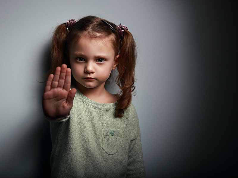 young girl holding up hand in "stop" gesture