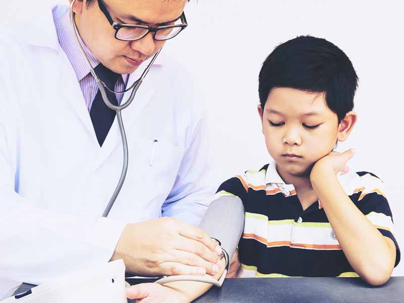 physician preparing to take young boy's blood pressure