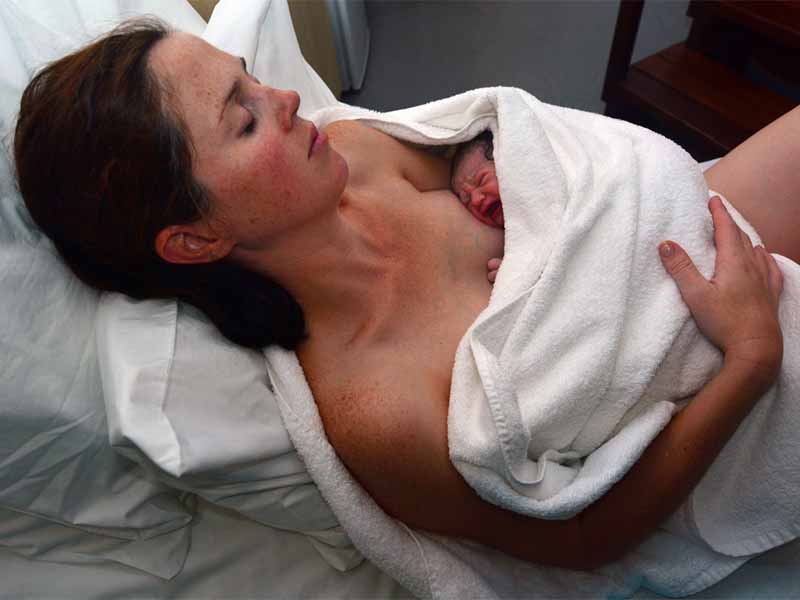 Mother rest with her newborn baby in bed immediately after a natural water birth labour. Concept photo of  pregnant woman, newborn, baby, pregnancy.