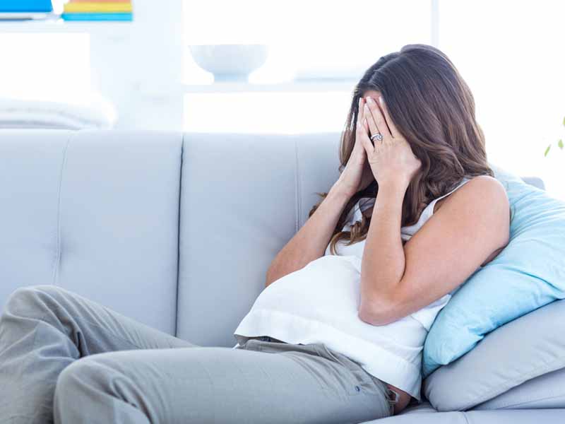 distressed pregnant woman on couch