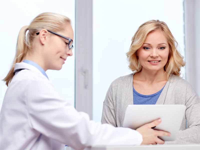 medicine, health care and people concept - smiling doctor with tablet pc computer and woman meeting at hospital