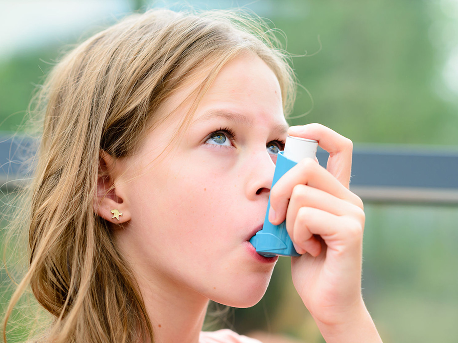 young girl using asthma inhaler