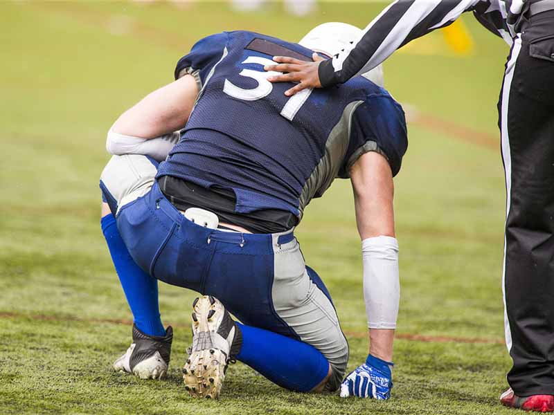 injured football player kneeling on field