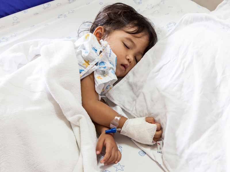 young girl with IV asleep in hospital bed