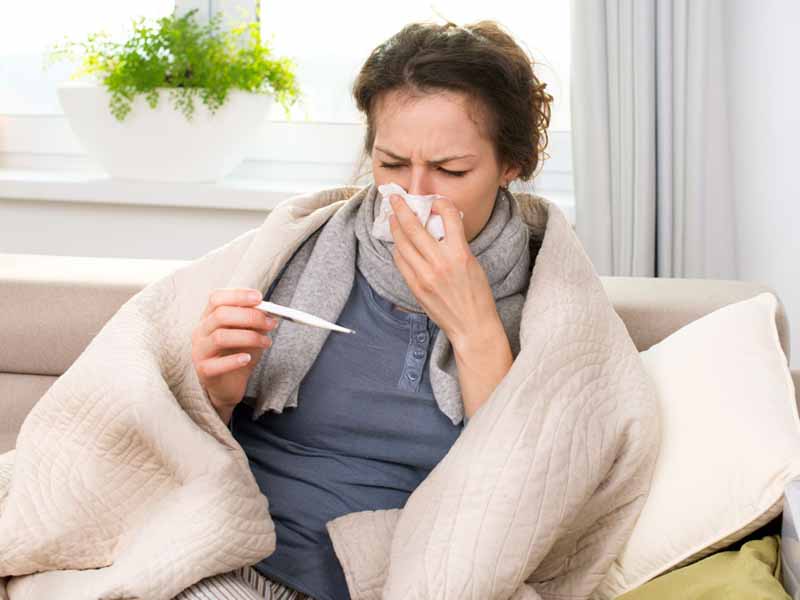 women with flu symptoms bundled up on couch