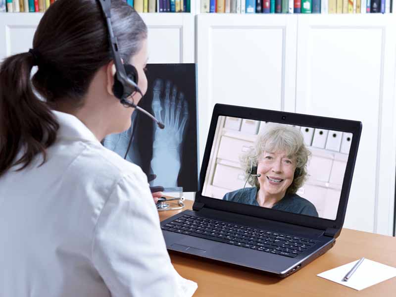 Female physician consulting with older woman via telemedicine