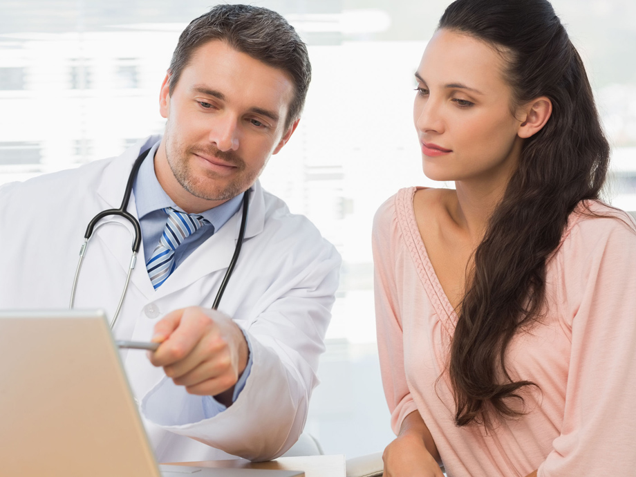 Male doctor showing something on laptop to patient in medical office