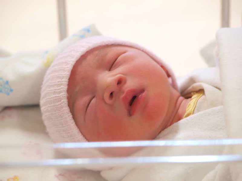 newborn lying in hospital bassinet