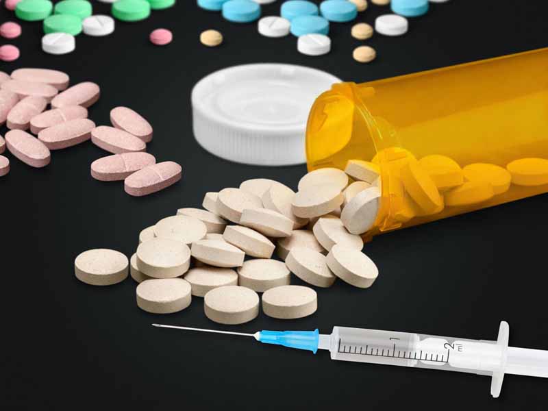prescription bottle surrounded by piles of pills, syringe
