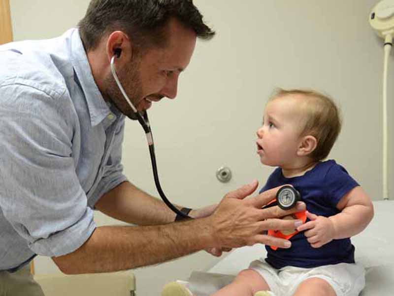 A family physician does a wellness check on a toddler
