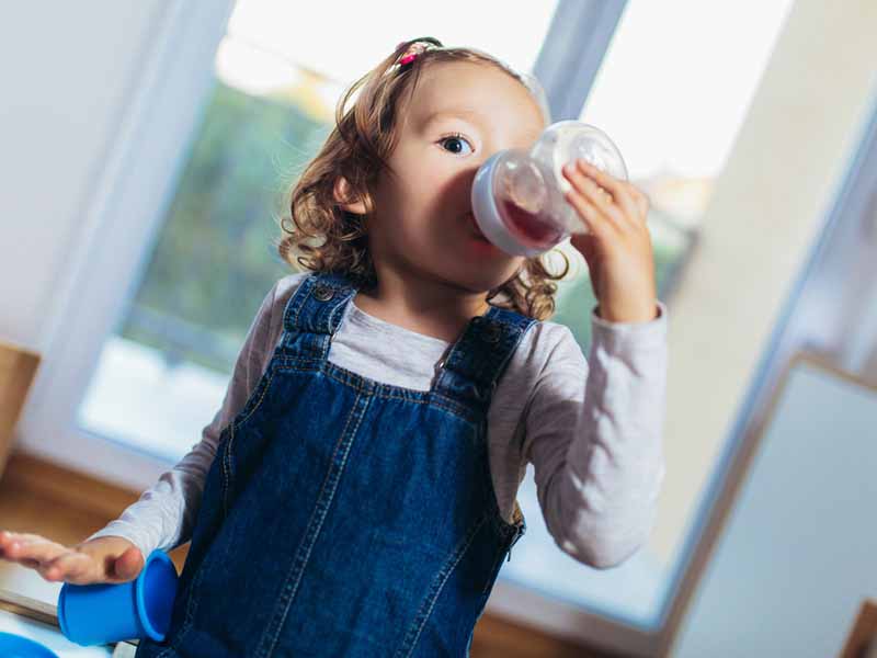 Adorable child drinking juice from bottle.