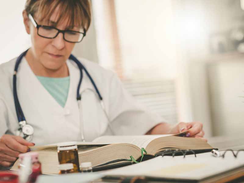 Female doctor reading a textbook in medical office