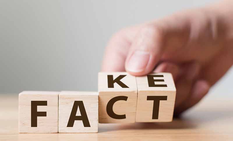 hand flipping letters on wooden blocks from 'fake' to 'fact'