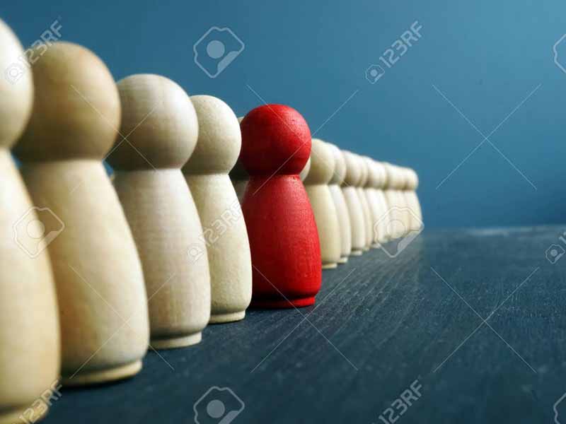 Leadership development. Line of wooden figurines with red one.