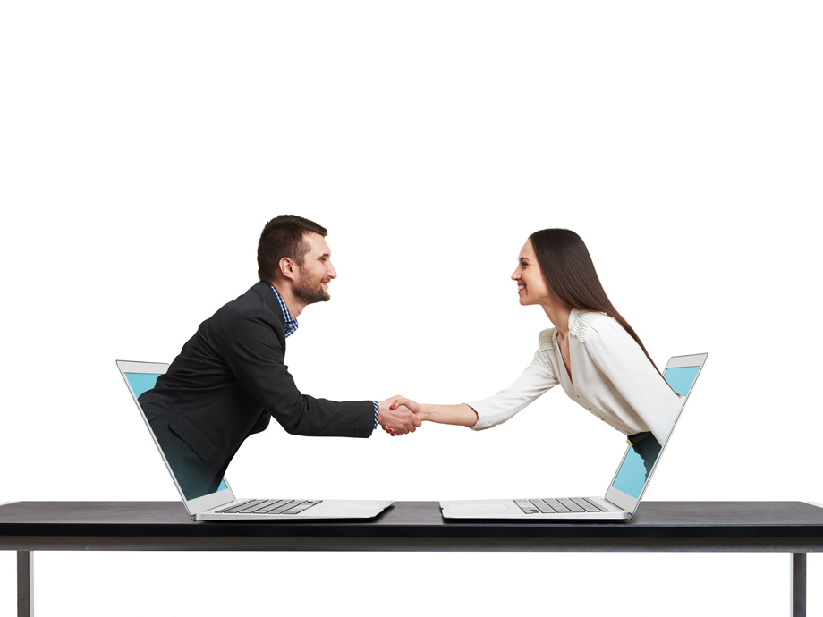 smiley businessman and businesswoman come out from laptop, shaking hands and looking at each other over white background