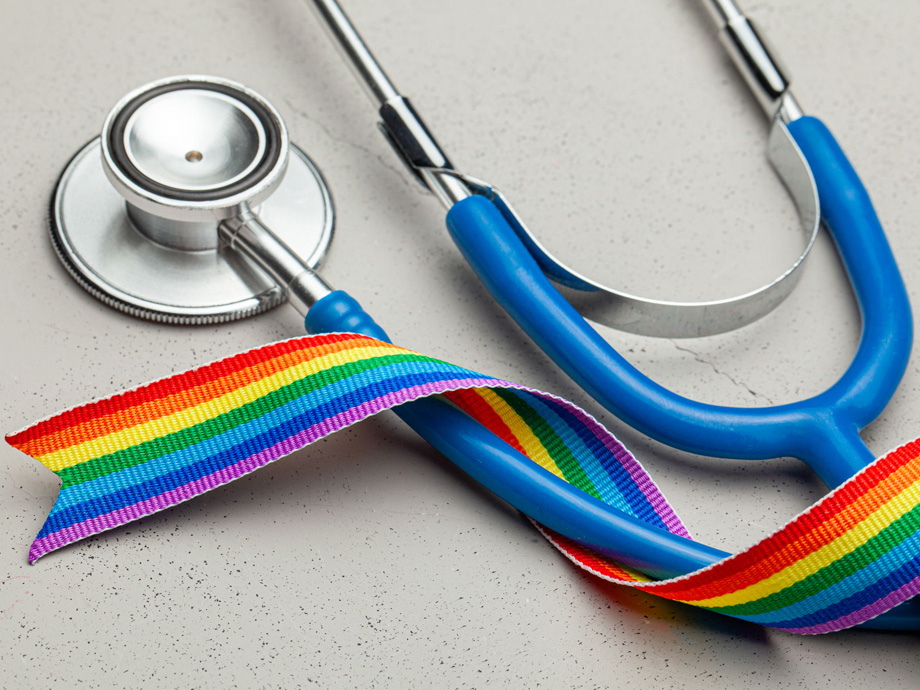 Stethoscope and LGBT rainbow ribbon pride symbol. Medical support after sex reassignment surgery. Grey background.