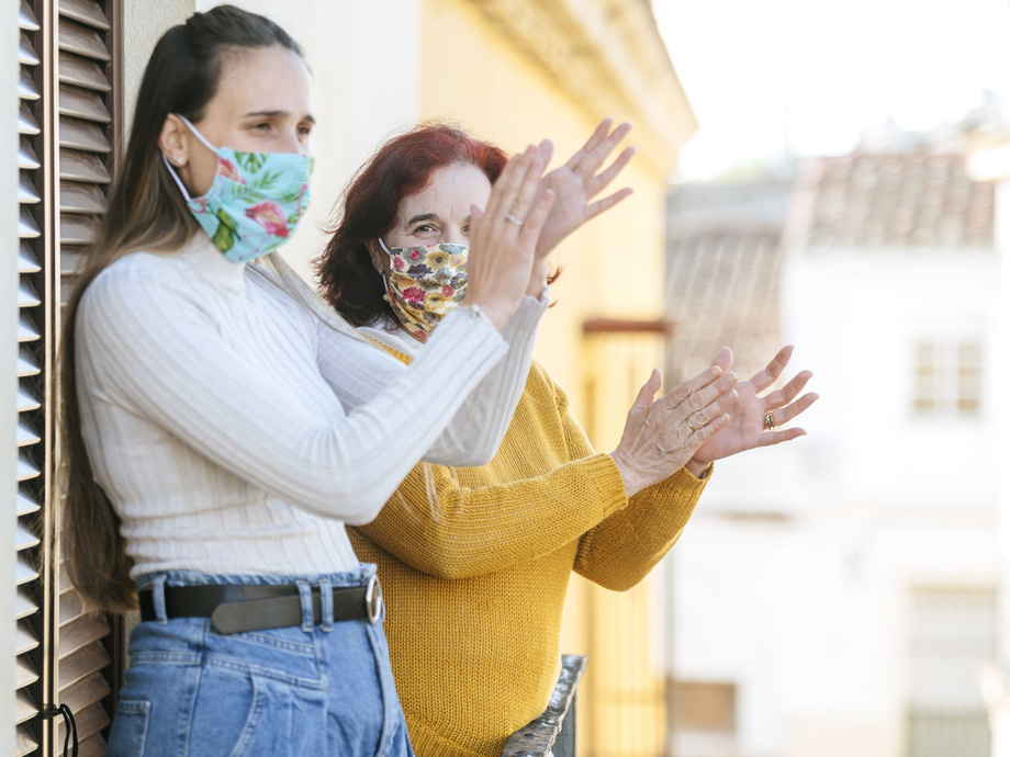 Two women with face mask clapping on the balcony
