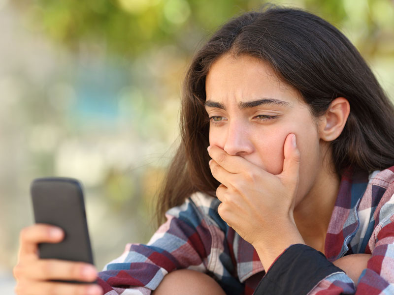 worried teen looking at smartphone