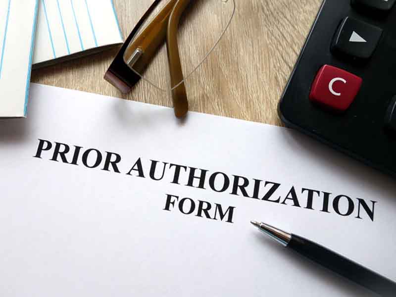 Prior authorization form with pen, calculator and glasses on desk