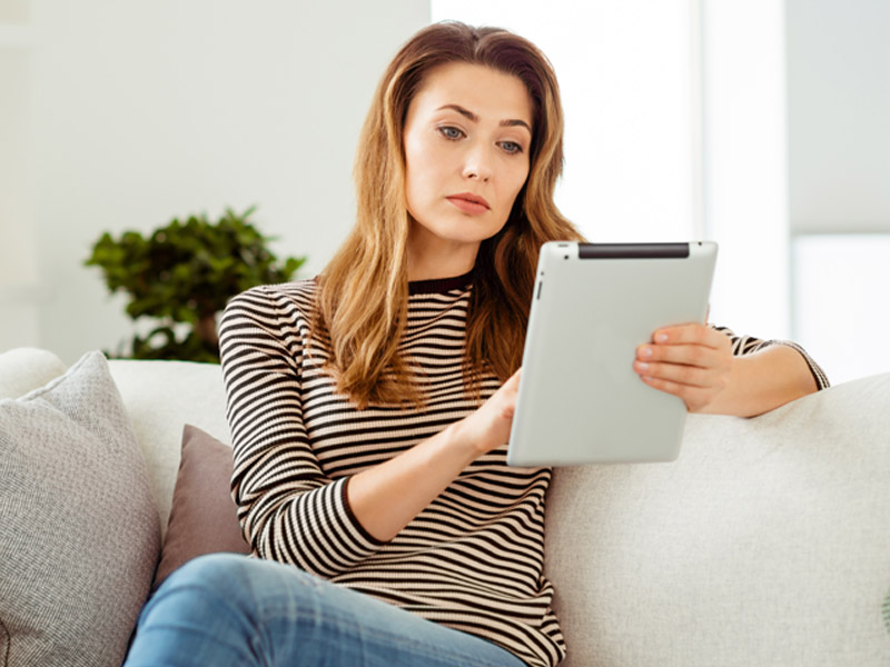 Woman looking at tablet on couch