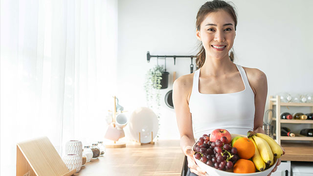 Woman holding bowl of fruit in a workout room