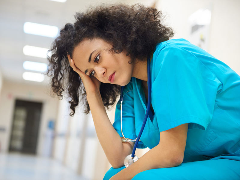 Serious young female doctor sitting in hospital corridor