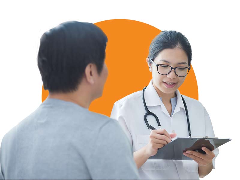 A female doctor meets with a male patient and writes on a clipboard.